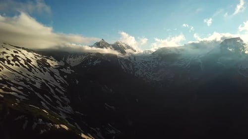 Vue aérienne des rayons du soleil à travers un paysage nuageux au-dessus des montagnes autrichiennes et des sommets enneigés