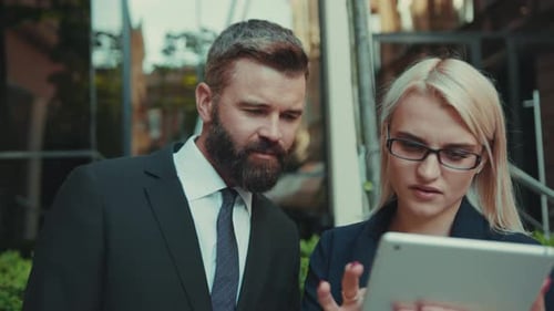 Business People Discussing Information on Tablet Outdoors