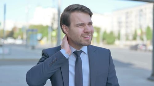 Man in Suit Rubbing Neck in Urban Setting