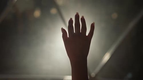 Hand Reaching Upward Silhouetted in Bright Light