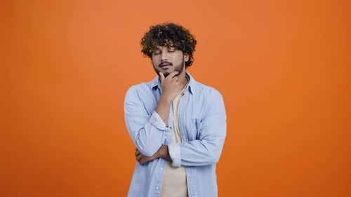 Young Man Thinking in Front of Orange Background