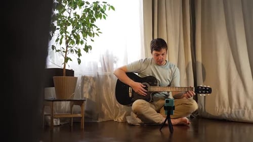 Man Plays Guitar at Home for Phone Camera