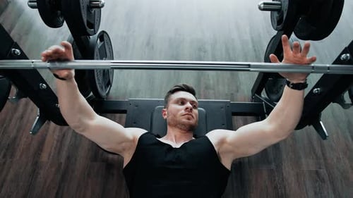 Young athlete doing bench press in gym