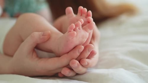 Adult Holding Infant's Tiny Feet in Hands