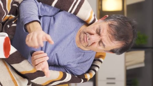 Man with Discomfort Rubbing Hands While Seated