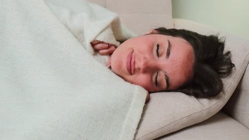 Dark-Haired Woman Sleeping Under Blanket Wakes Up Smiling