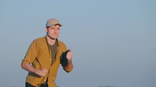 A Young Ermer with a Tablet in His Hand Dances in a Field