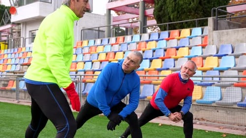 Senior Men Stretching Leg Muscles at Stadium