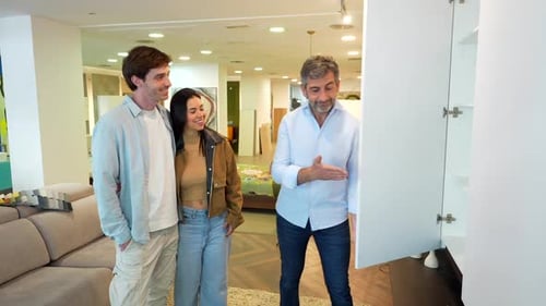 Couple choosing furniture in a showroom with a shop assistant