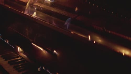 A fire burns up a piano in the dark