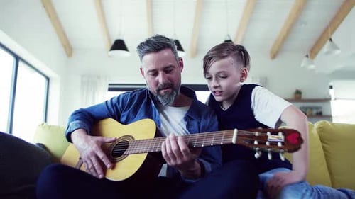Father and Son Playing Guitar on the Sofa