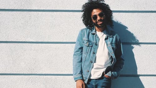 Man with Curly Hair Posing Against White Wall