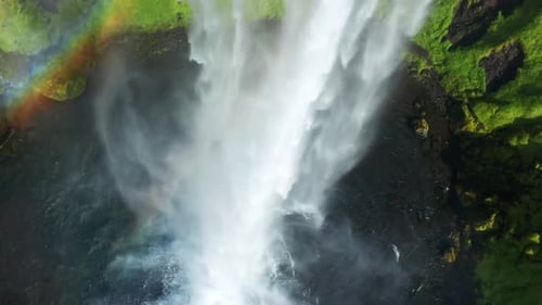 Majestic Waterfall Plunging into Canyon with Vibrant Rainbow and Green Cliffs