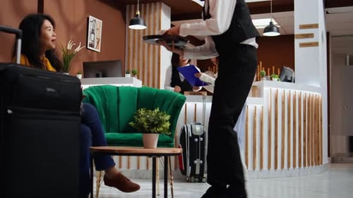 Hotel Guest Reading and Signing Registration Forms in Lobby