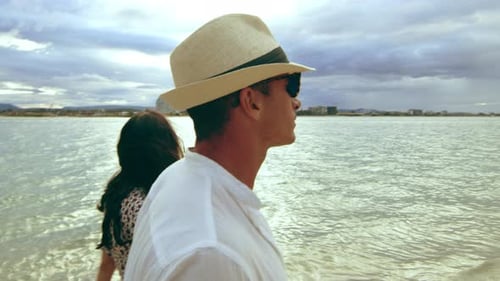 Beautiful Young Caucasian Couple Walking on the Beach, Holding Hands Under A