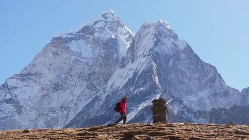 Hiker in Red Jacket Trekking Through the Majestic Himalayas of Nepal with SnowCapped Peaks in the