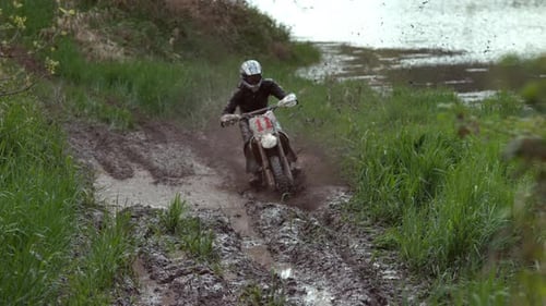 Man on dirtbike races through muddy track