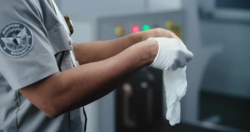 Airport Security Puts On Gloves Before Scanning Luggage