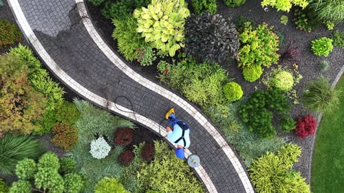Gardener Pressure Washing Garden Path Aerial View.