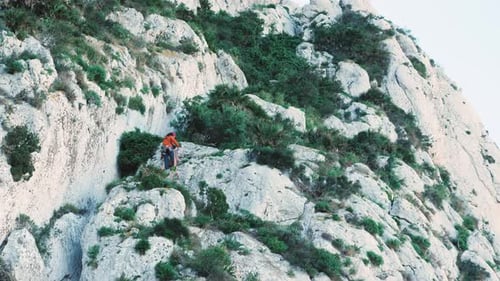 Man rock climber in protective helmet climbing rock mountain using rope