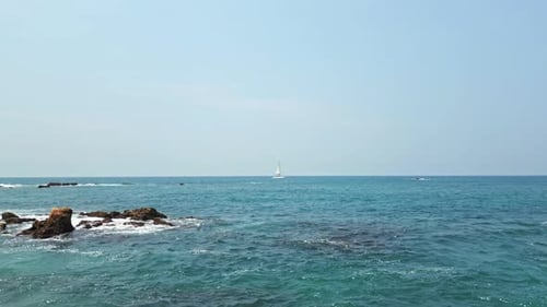 Segelyachtkreuzfahrten an der felsigen Küste an einem sonnigen Tag vorbei Das klare blaue Meer umgibt das Schiff beim Navigieren