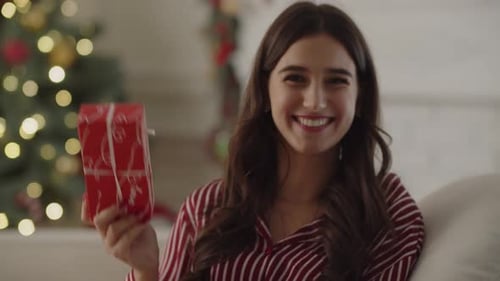 Woman Excitedly Holds Christmas Gift at Home