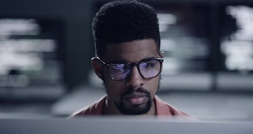 Vidéo 4K d'un jeune programmeur regardant son écran alors qu'il travaille tard dans la nuit
