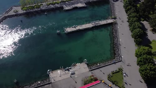 Luftneigung nach oben über einem Restaurant und Anlegestelle am Genfersee in Lausanne, Schweiz, an einem sonnigen