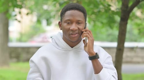 African Man Talking on a Smartphone in a Park