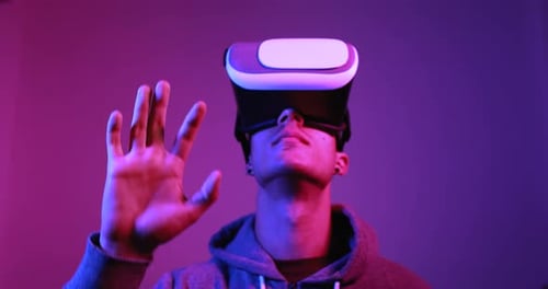 Smiling millennial man enjoys virtual reality experience inside modern studio