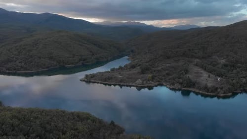 Drone mountain lake reflecting colorful sunset clouds tilt up mountain peaks