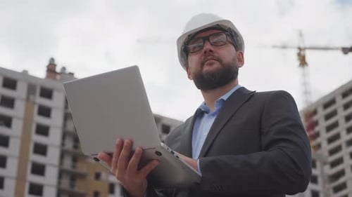 Civil Engineer in Suit and Protective Helmet Making Important Notes in Notebook