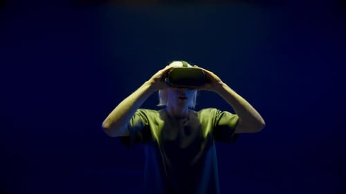 Man Takes Off VR Headset in Neon Lighting
