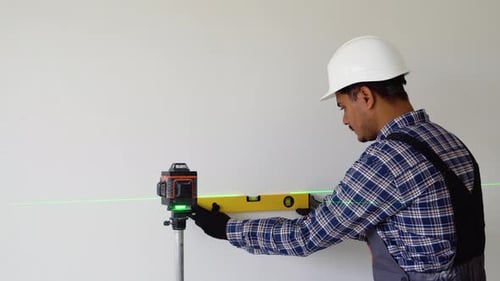 Indian Worker Measuring Walls with Laser Level Tool