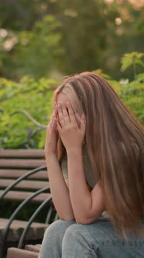 Contemplative Woman Sitting on Park Bench Surrounded By Greenery in Reflective Mood