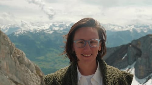 Portrait of smiling female with snowy rocky mountain summits on horizon