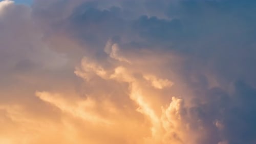 Fluffy Clouds Rolling Across Blue Sky at Sunset