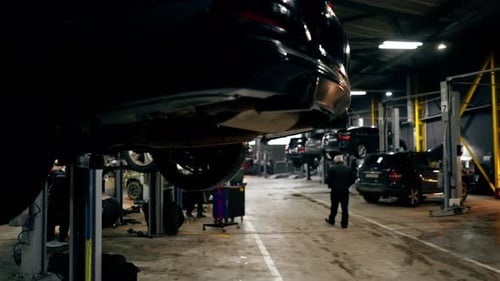 Closeup of a Part of the Rear Bumper on Lift at a Service Station Against the Background of Other