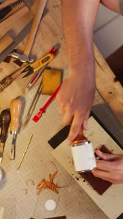 Worker Taps Tool with Hammer to Make Holes in Leather