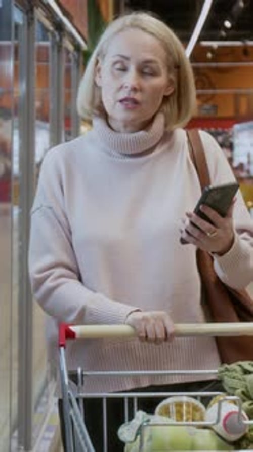 Mature Woman using Phone in Grocery Store