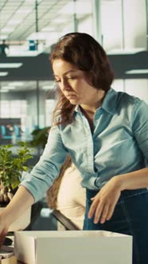 Vidéo verticale bouleverse un travailleur de bureau qui emballe des plantes de bureau le dernier jour de travail