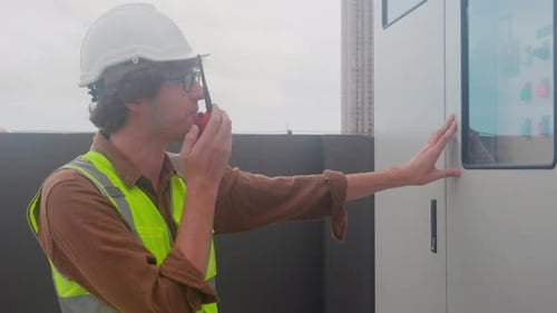 Construction Worker Using Walkie Talkie Near Electrical Panel