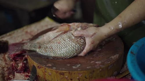 Marktverkäufer in Zeitlupe, der rohen Fisch mit einem scharfen Messer auf einem runden Brett schneidet