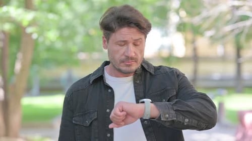Man Checks Watch, Waits in Sunny Park