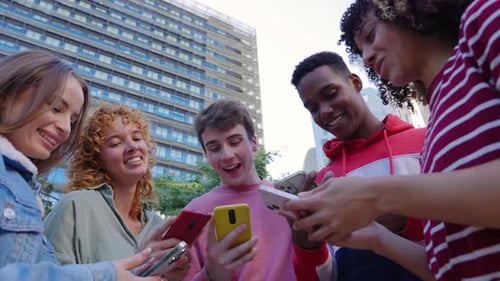 Smiling Friends Sharing Content on Smartphones in City