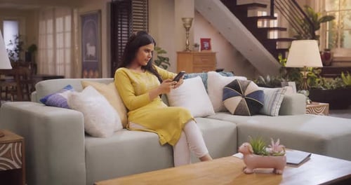 Woman Using Smartphone on Sofa in Living Room