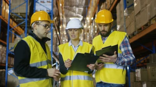 Team of Male and Female Inspectors/ Workers/Auditors Have Discussion in Big Warehouse with Rows of