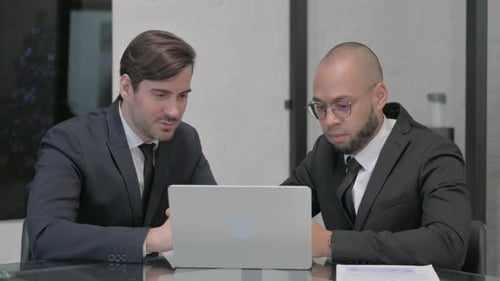 Businessmen Collaborate on Laptop in Modern Workspace