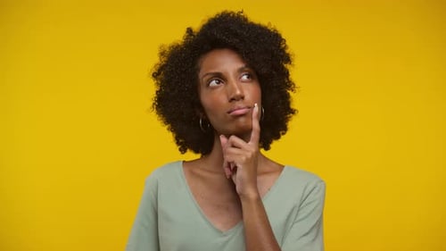 Young Woman Thinking Against Yellow Background