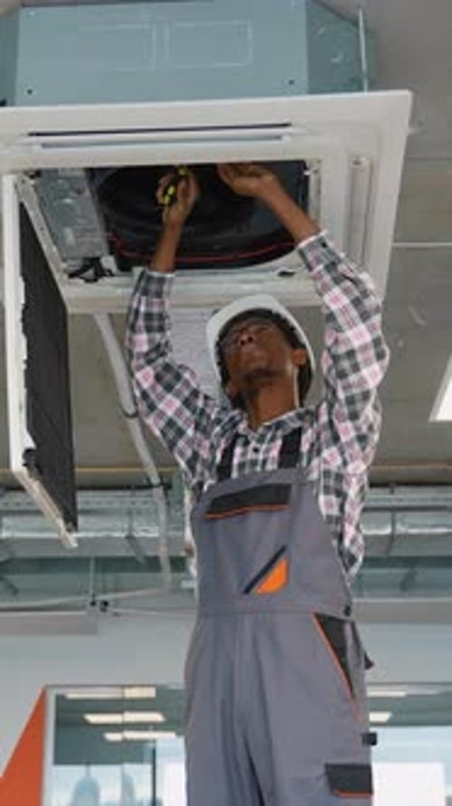 Man Repairing Air Conditioner at Workplace